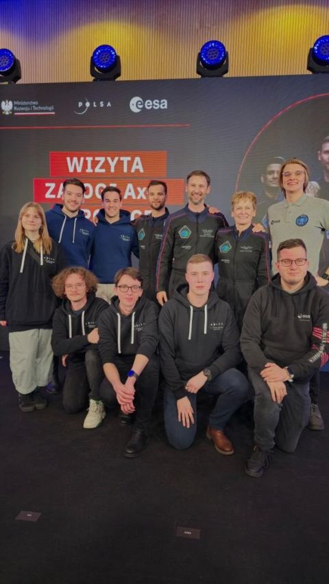 Wspólne zdjęcie przed planszą „Wizyta załogi Ax-4 w Polsce”